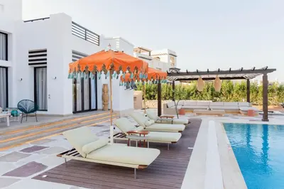 a pool with lounge chairs and an orange umbrella at The Reef House Luxury Waterfront Villa in Hurghada