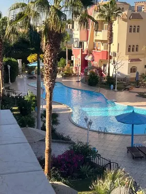 a resort swimming pool with a palm tree and buildings at green garden resort in Hurghada