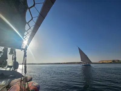 a boat in the water with a sail on the water at Aswan all-inclusive private felucca in Aswan