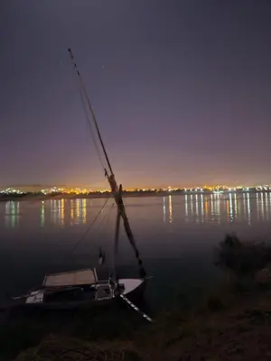 a boat sitting on the water at night at Aswan all-inclusive private felucca in Aswan