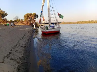 a boat on the shore of a body of water at Aswan all-inclusive private felucca in Aswan