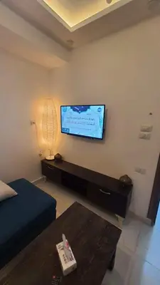 a living room with a flat screen tv on the wall at La Luna Garden Magawish in Hurghada