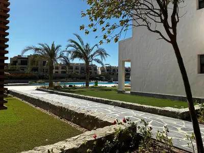a walkway in front of a building with palm trees at 1BR Chalet at Makadi Heights Hurghada in Hurghada