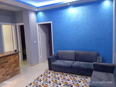 a living room with a couch and a blue wall at Red Ruby chalets &flats HRG,Elgouna in Hurghada