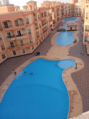 a view of three swimming pools in front of buildings at Red Ruby chalets &flats HRG,Elgouna in Hurghada