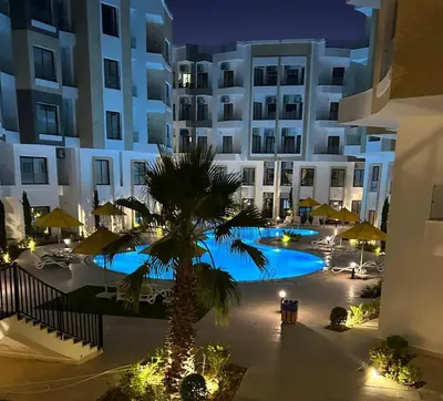 a hotel with a palm tree in front of a building at Aqua infinity resort in Hurghada