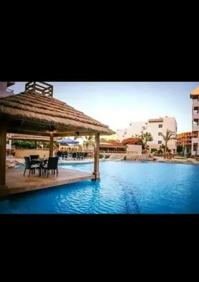 a pavilion with a table and chairs next to a pool at قريه الدهبيه in Hurghada
