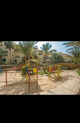 a playground in a park with trees and buildings at قريه الدهبيه in Hurghada