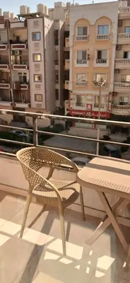 a chair and a table on a balcony with buildings at Hurghada Tiba Golden Beach Resort Down Town in Hurghada