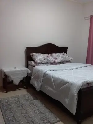 a bedroom with a bed and a nightstand next to it at Rich Home Hurghada in Hurghada