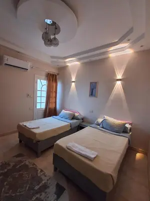 two beds in a room with lights on the wall at El Agamy Hotel Apartment in Luxor