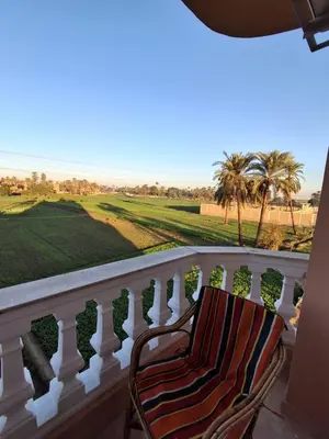 a chair on a balcony looking out at the golf course at El Agamy Hotel Apartment in Luxor