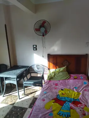 a bedroom with a bed and a chair and a fan at شقة صغيرة قريبة من شاطئ البحر في سفاجا in Safaga