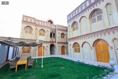 a building with a table and chairs in a yard at Nefertari Palace apartments in Al Aqālitah