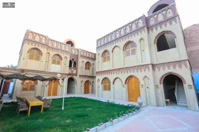a large building with a grass yard in front of it at Nefertari Palace apartments in Al Aqālitah