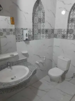 a white bathroom with a toilet and a sink at Nefertari Palace apartments in Al Aqālitah