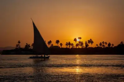 a boat with a sail in the water at sunset at NOOR SEEN House in Luxor