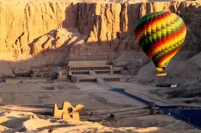 a hot air balloon flying over a building in the desert at NOOR SEEN House in Luxor