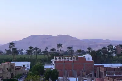 a city with buildings and palm trees and mountains at Qasr El Nil in Luxor
