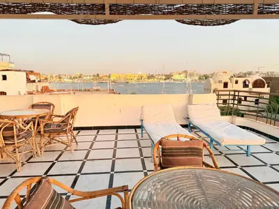 a balcony with chairs and tables and a view of the water at Qasr El Nil in Luxor