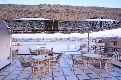 a patio with tables and chairs and a view of the water at Qasr El Nil in Luxor