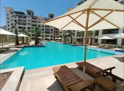 a swimming pool with a bench and an umbrella at Lotus Al-Dau Heights in Hurghada