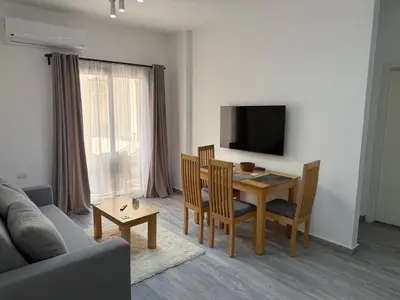 a living room with a table and chairs and a television at Imperial Resort App 433 in Hurghada