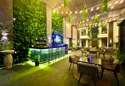 a restaurant with a green wall and tables and chairs at Imperial Resort App 433 in Hurghada