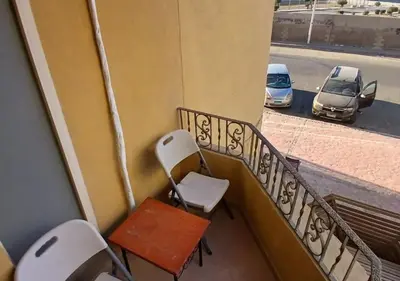 a balcony with chairs and a table and cars on a street at Modern Apartment in the Britsh Resort in Hurghada
