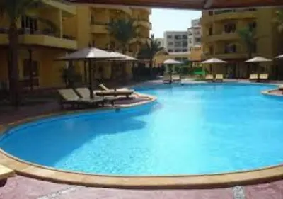 a large blue swimming pool with chairs and umbrellas at Modern Apartment in the Britsh Resort in Hurghada