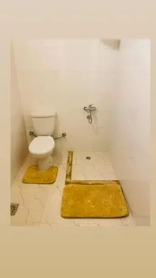 a bathroom with a toilet and two yellow rugs at In Luxor in Luxor