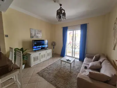 a living room with a couch and a tv at Stunning One-Bedroom Apartment at the prestigious Palm Beach Piazza in Hurghada