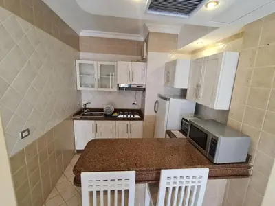 a small kitchen with white cabinets and a microwave at Stunning One-Bedroom Apartment at the prestigious Palm Beach Piazza in Hurghada