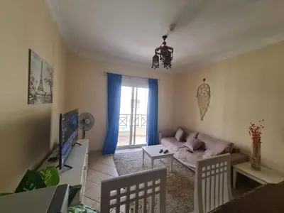 a living room with a couch and a tv at Stunning One-Bedroom Apartment at the prestigious Palm Beach Piazza in Hurghada