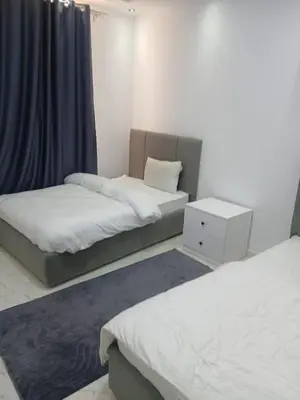 a bedroom with two beds and a blue curtain at Luona House in ‘Ezbet Abu Ḥabashi