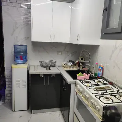 a kitchen with white cabinets and a stove top oven at Appartement 2 slaapkamers in Hurghada