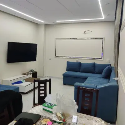 a living room with a blue couch and a flat screen tv at Appartement 2 slaapkamers in Hurghada