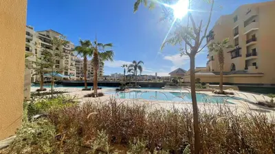 a swimming pool with palm trees and buildings at Luxury apartment pool view in Hurghada