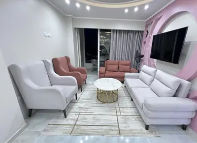 a living room with white furniture and a tv at Hobby live in Hurghada in Hurghada
