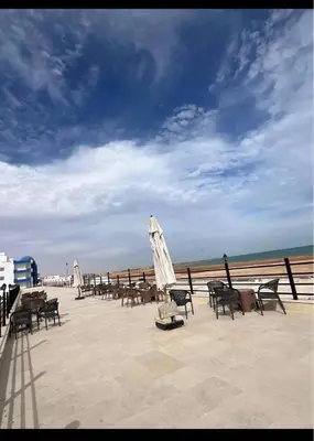a group of tables and chairs and an umbrella on the beach at اوسيس مارينا in Hurghada
