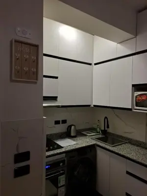 a kitchen with white cabinets and a sink and a stove at Cozy flat in Makadi Heights in Hurghada