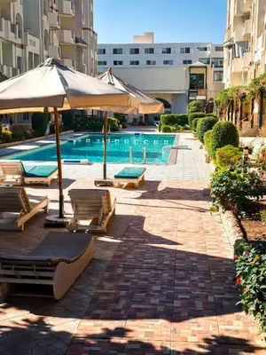 a swimming pool with chairs and umbrellas next to a building at Apartman v Hurgade 2 izbovy , v rezorte Florenza,plne zariadeny in Hurghada