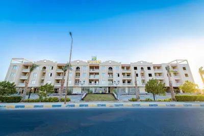 a large white building with palm trees in front of it at Avin Resort in Hurghada