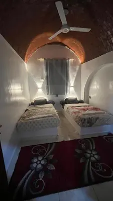 two beds in a room with a ceiling fan at Sheba Kato in Jazīrat Aswān