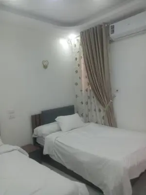 a hotel room with two beds and a window at Luxor Hostel Place in Al Baghdādī
