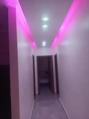 a hallway with pink lights on a white wall at Luxor Hostel Place in Al Baghdādī