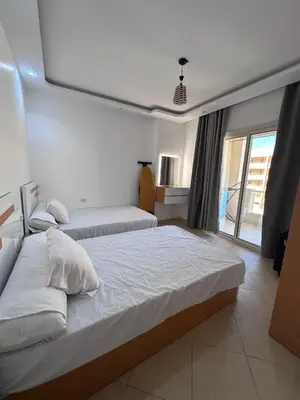a bedroom with two beds and a window at Ezz in Hurghada