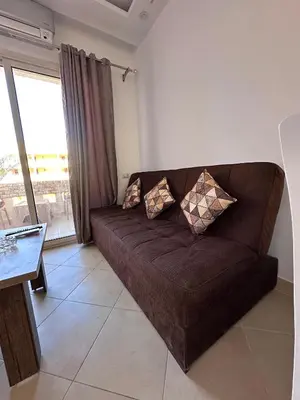 a brown couch in a living room with a window at Ezz in Hurghada