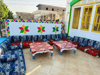 a patio with couches and tables on a building at Kuliih guest house in Jazīrat Suhayl