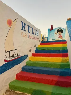 a rainbow colored cake with a sign on a beach at Kuliih guest house in Jazīrat Suhayl